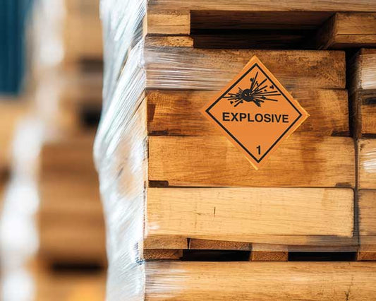 Holzkisten mit Gefahrgutkennzeichnung für explosive Stoffe der Klasse 1 in Lagerumgebung